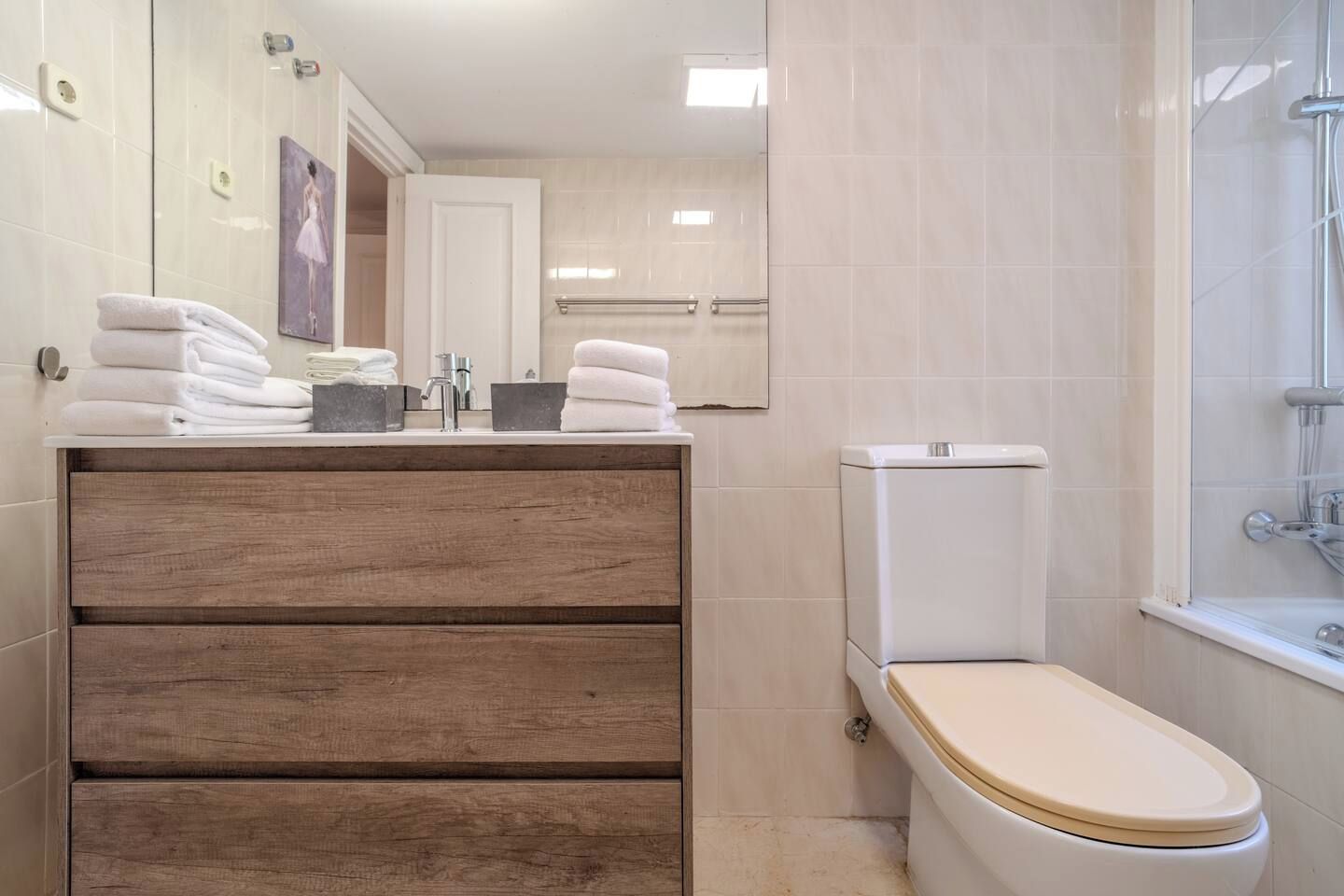 A bathroom with a wooden vanity, a toilet, and a shower area.