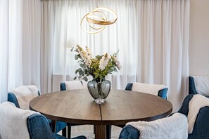 A round dining table with a vase of flowers in the center, surrounded by chairs with blue upholstery. - LAG - Spacious townhouse with private jacuzzi (Benahavis)