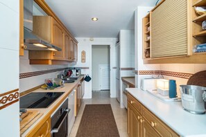 A compact kitchen with wooden cabinets, a built-in oven, and a countertop with various appliances. - LAG - Spacious townhouse with private jacuzzi (Benahavis)