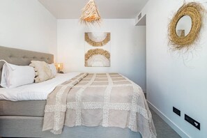 A bedroom with a bed, a wall-mounted mirror, and a decorative wall piece. - LAe112D - Large terrace with stunning views (Estepona)