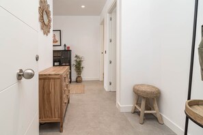 A hallway with a wooden cabinet, a woven stool, and a potted plant. - LAe112D - Large terrace with stunning views (Estepona)