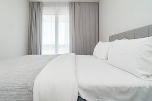 A neatly made bed with white linens in a room with a grey headboard and sheer curtains. - Apartment with 3BR, garden, pool & gym - JG5. 4A (Marbella)
