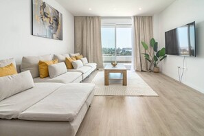 Een moderne woonkamer met een zithoek, een salontafel en een flatscreen televisie.