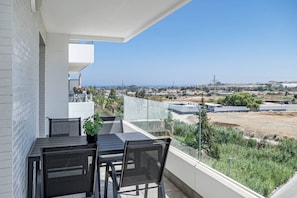 A balcony with a table and chairs, overlooking a residential area with houses and a clear sky. - Apartment with 3BR, garden, pool & gym - JG5. 4A (Marbella)