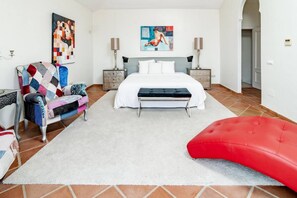 A bedroom with a bed, a colorful armchair, a red ottoman, and artwork on the walls. - LAP- 3 bed apartment on the beach. Families only (Bahía de Casares)