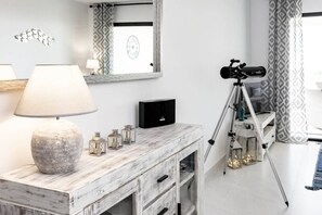 A room with a wooden vanity, a lamp, a mirror, a telescope, and patterned curtains. - Luxury Resort Apt with Sea View & Pools - LAE23i (Estepona)