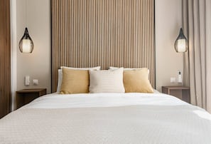 A hotel room with a large bed, a wooden slat headboard, two bedside tables, and two wall-mounted lamps. - Jm94 - Totally renovated in stylish design (Mijas)
