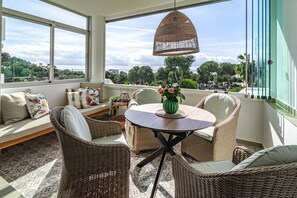 A sunlit room with wicker furniture, a round table, and a hanging light fixture. - Jm94 - Totally renovated in stylish design (Mijas)