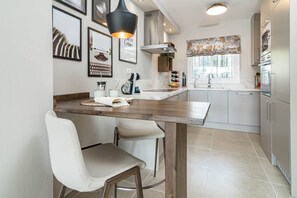 A modern kitchen with a wooden island, white bar stools, and a hanging light fixture. - Jm94 - Totally renovated in stylish design (Mijas)