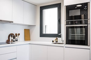 Eine moderne Küche mit weißen Schränken, einem großen Fenster und einem eingebauten Backofen.