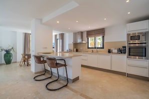A modern kitchen with a central island, bar stools, and built-in appliances. - JDG7-Stunning holiday home 100 meters from beach (Marbella)