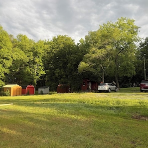 A campground with multiple small cabins, a red building, and a white car parked in the grass. - Country Ocean 2 bedroom home near the forest (Salisbury)