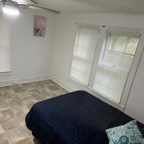 A bedroom with a bed, a window with blinds, a ceiling fan, and a wall-mounted light fixture. - Country Ocean 2 bedroom home near the forest (Salisbury)