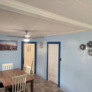 A dining area with a table and chairs, a ceiling fan, and a door with a blue frame. - Country Ocean 2 bedroom home near the forest (Salisbury)
