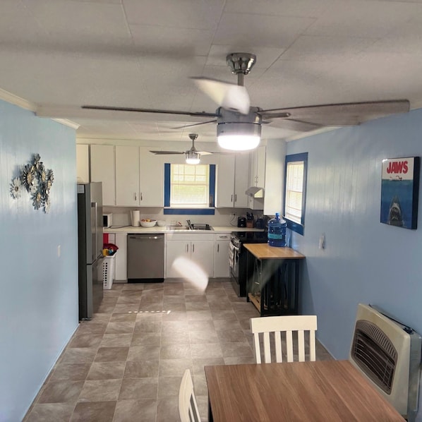 A compact kitchen with white cabinets, a dining table, and a ceiling fan. - Country Ocean 2 bedroom home near the forest (Salisbury)