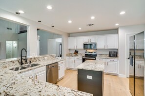 A modern kitchen with white cabinets, granite countertops, stainless steel appliances, and a central island. - Spacious 5-bedroom Luxury Villa with Pool, Parking in peaceful Burleson (Burleson)