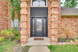 A brick house with a dark front door, a small porch, and a window above the door. - Spacious 5-bedroom Luxury Villa with Pool, Parking in peaceful Burleson (Burleson)
