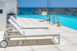 A poolside area with lounge chairs, a lifebuoy, and a view of the sea. - INf46P - Spacious holiday home in Estepona (Estepona)