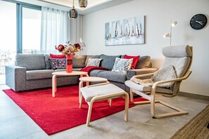 A modern living room with a grey sofa, red rug, and a chair with a white cushion. - INf46P - Spacious holiday home in Estepona (Estepona)