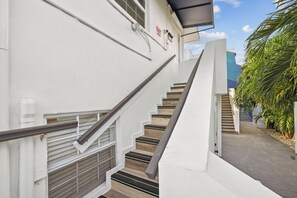 Eine Treppe mit Handlauf führt zu einer Tür, über der ein 'EXIT'-Schild angebracht ist.