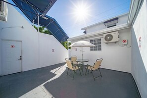 Eine Terrasse mit Tisch, Stühlen und Sonnenschirm, sowie eine Tür mit einem Schild.