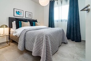 A bedroom with a bed, a nightstand, a lamp, and a window with curtains. - INf45P- modern 3 bed city apartment next to beach (Estepona)