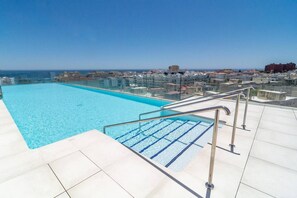 A rooftop swimming pool with clear blue water, surrounded by a white tiled deck and metal railings. - INf45P- modern 3 bed city apartment next to beach (Estepona)