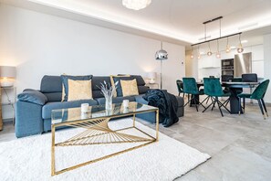 A modern living room with a sofa, coffee table, and dining area with chairs. - INf45P- modern 3 bed city apartment next to beach (Estepona)