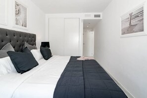 Ein Schlafzimmer mit einem großen Bett, einem Kopfteil und einer Tür zu einem anderen Raum.