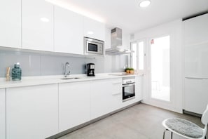 A modern kitchen with white cabinets, a built-in microwave, a coffee maker, and an oven. - IVY - Scandinavian Apartment in Nueva Andalucia (Marbella)
