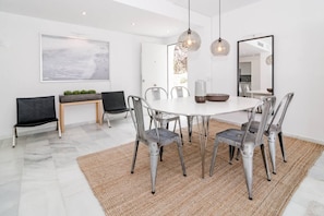 A modern dining area with a round table, metal chairs, a bench, and hanging pendant lights. - IVY - Scandinavian Apartment in Nueva Andalucia (Marbella)