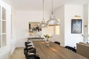 A dining area with a long wooden table, black chairs, and two pendant lights. - LBP - 3 Bedroom Penthouse in Nueva Andalucia (Marbella)