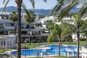 A hotel with a swimming pool, palm trees, and a mountainous backdrop. - LCR4 - Large 3-Bedroom Apartment Near Beach (Marbella)