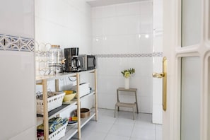 A kitchen with white tiled walls, a coffee maker, a microwave, and a shelf with various items. - LCR4 - Large 3-Bedroom Apartment Near Beach (Marbella)