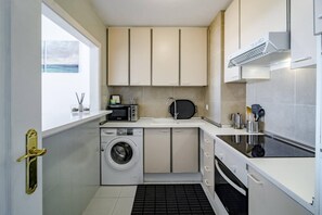 Cozinha compacta com máquina de lavar, micro-ondas, pia e fogão.
