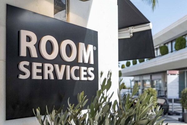 Placa com a inscrição 'ROOM SERVICES' na fachada de um edifício.