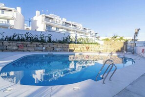 A swimming pool with a stone wall and a lifebuoy, surrounded by a white building and a clear sky. - LM10bb- Modern Living with Large sunny terrace (Estepona)