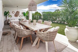 An outdoor dining area with a wooden table and wicker chairs, surrounded by potted plants and decorative wall art. - LM10bb- Modern Living with Large sunny terrace (Estepona)