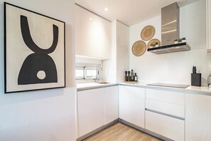 A modern kitchen with white cabinets, a stainless steel range hood, and a window above the sink. - LM10bb- Modern Living with Large sunny terrace (Estepona)