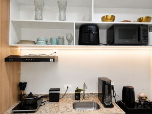 Eine moderne Küche mit einer eingebauten Mikrowelle, einer Kaffeemaschine und einem Wasserkocher auf der Arbeitsfläche.
