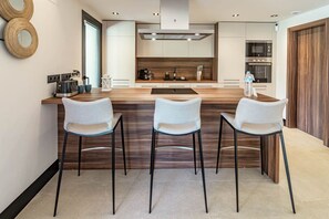 A modern kitchen with a central island, three bar-style chairs, and built-in appliances. - ML2B1- Stunning holiday home in Marbella (Marbella)
