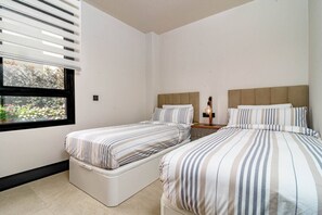 A hotel room with two beds, a window with blinds, and a bedside table with a lamp. - ML2B1- Stunning holiday home in Marbella (Marbella)