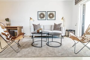 Un salon moderne comprenant un canapé, deux fauteuils, une table basse et deux lampadaires.