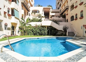 A swimming pool surrounded by a multi-story building with balconies and a staircase leading to an upper level. - MBb53 - Beachfront Penthouse with Sea views (Estepona)