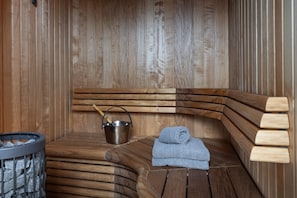 A sauna with wooden benches, a metal bucket, and a towel. - Mountain Lodge Idrefjäll (Idre)