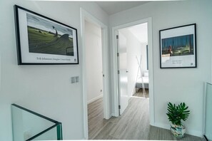 A hallway with framed artwork, a staircase, and a plant. - LMT46 - Modern Style Spacious Townhouse (Estepona)