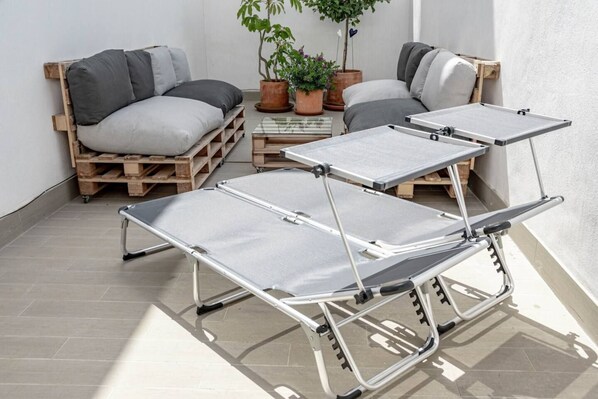 A room with a sofa set, a coffee table, and a metal folding table. - LMT46 - Modern Style Spacious Townhouse (Estepona)