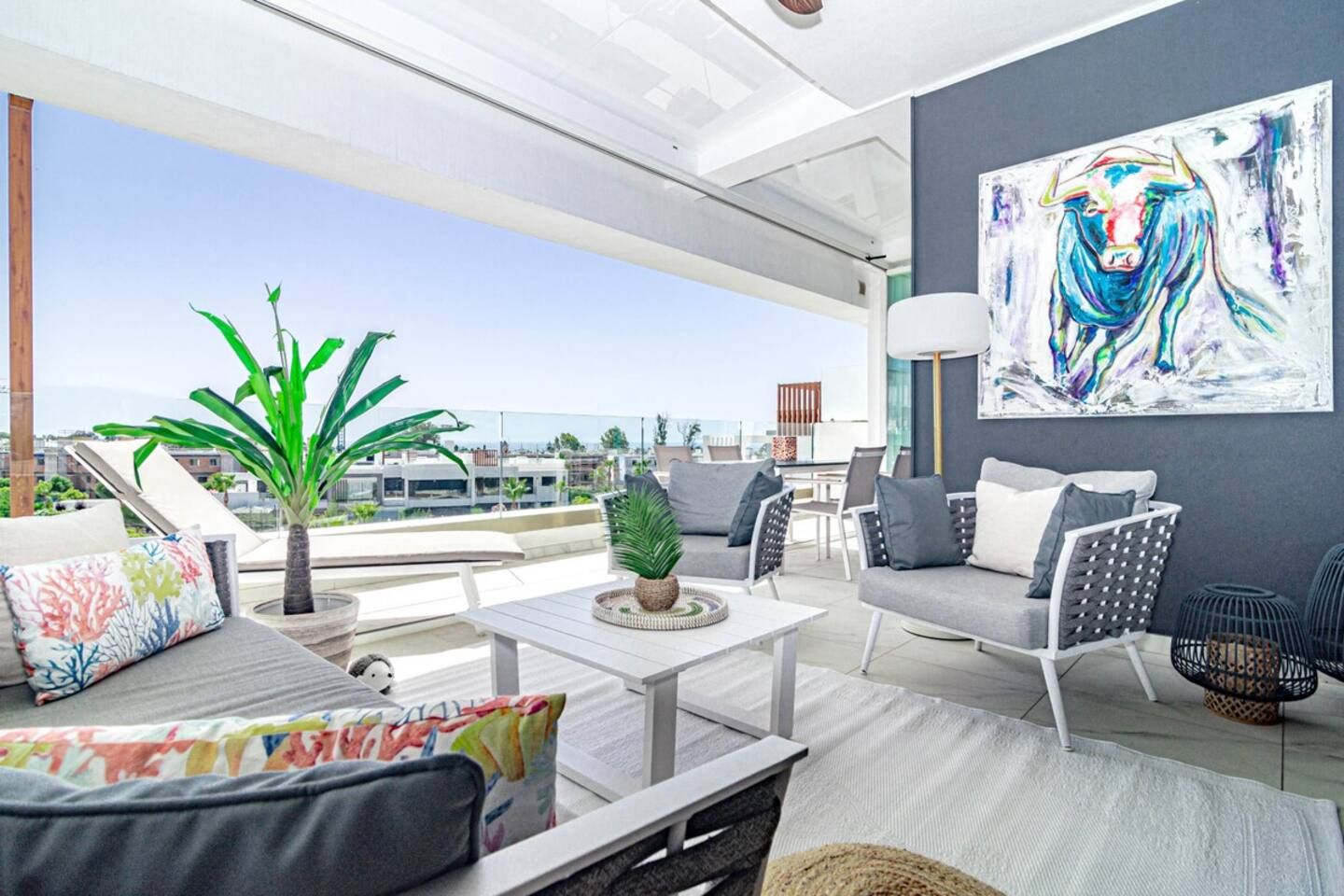 A modern outdoor living space with a sofa, chairs, a table, and a potted plant.