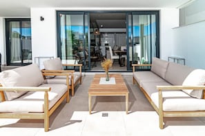 A modern living room with two sofas, a coffee table, and a dining area visible through glass doors. - LMe4BB Sb4bb- apotel las mesas by roomservices (Estepona)