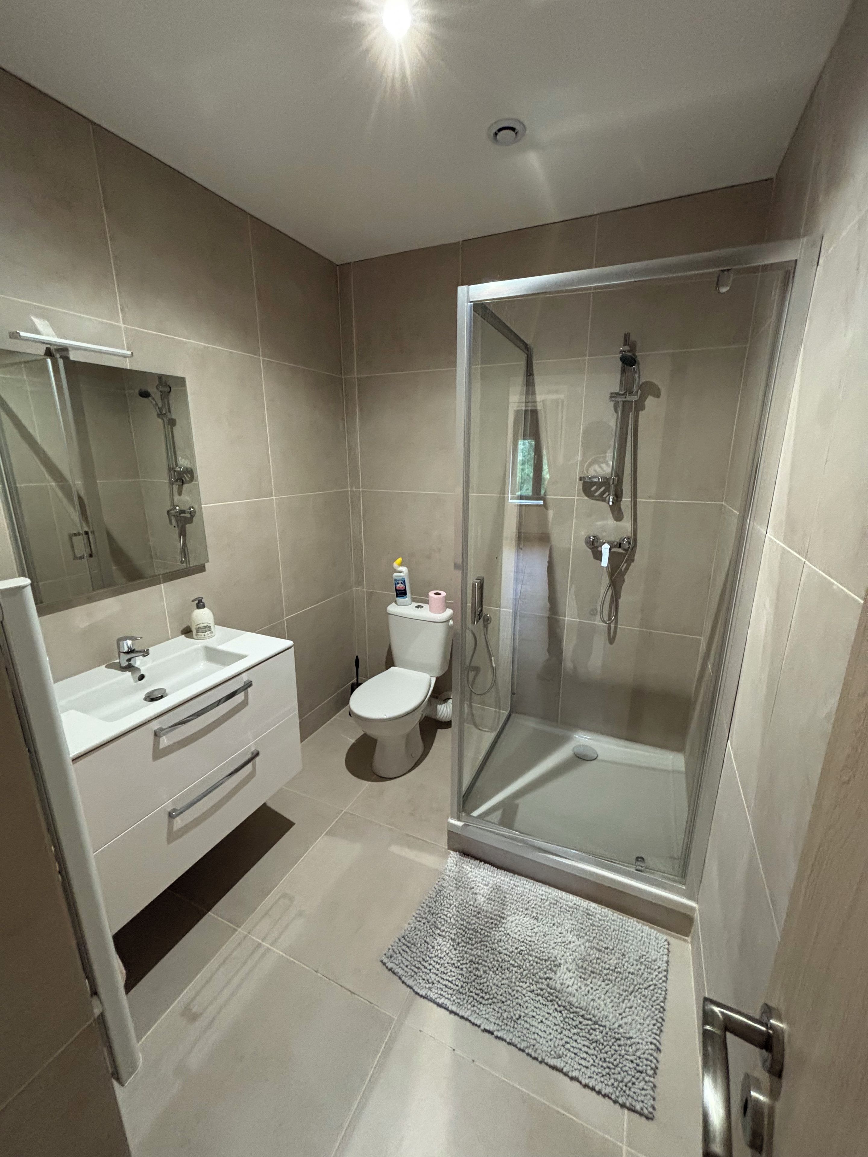 A modern bathroom with a glass-enclosed shower, a white sink, and a toilet.